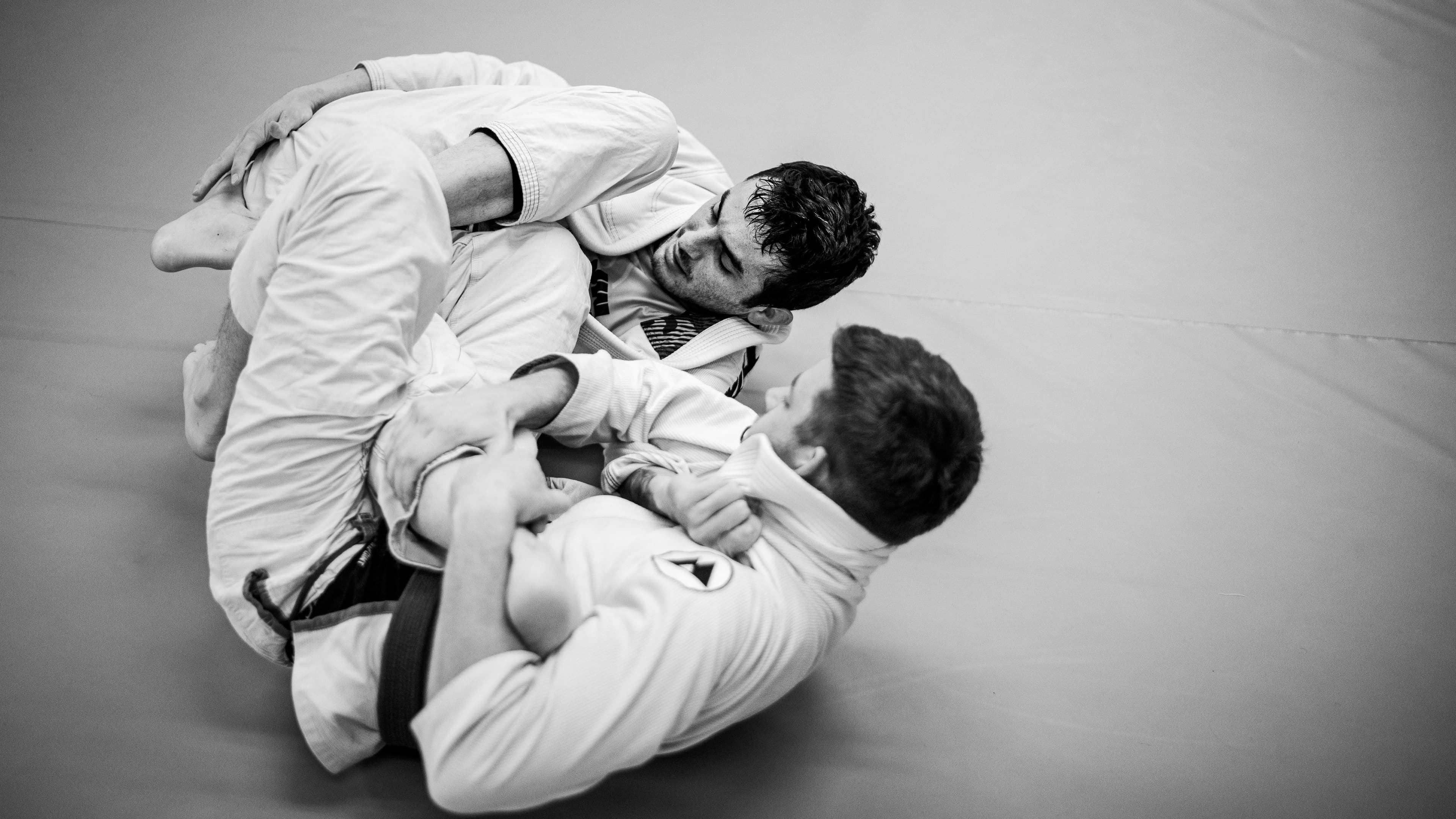 Two training partners in brazilian jiu jitsu gis that are sparring (also known as "rolling").